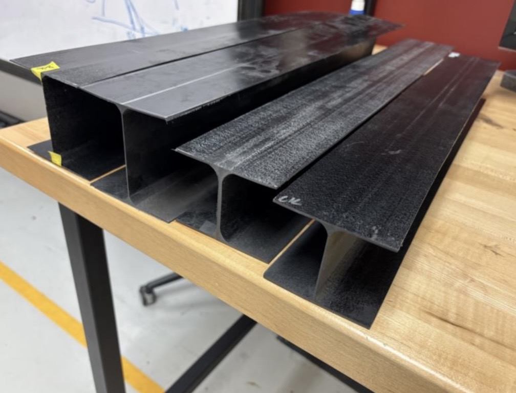 Finished carbon fiber I-beams on a workbench