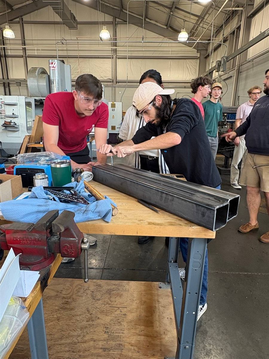 Team working on steel tubing at a shop bench