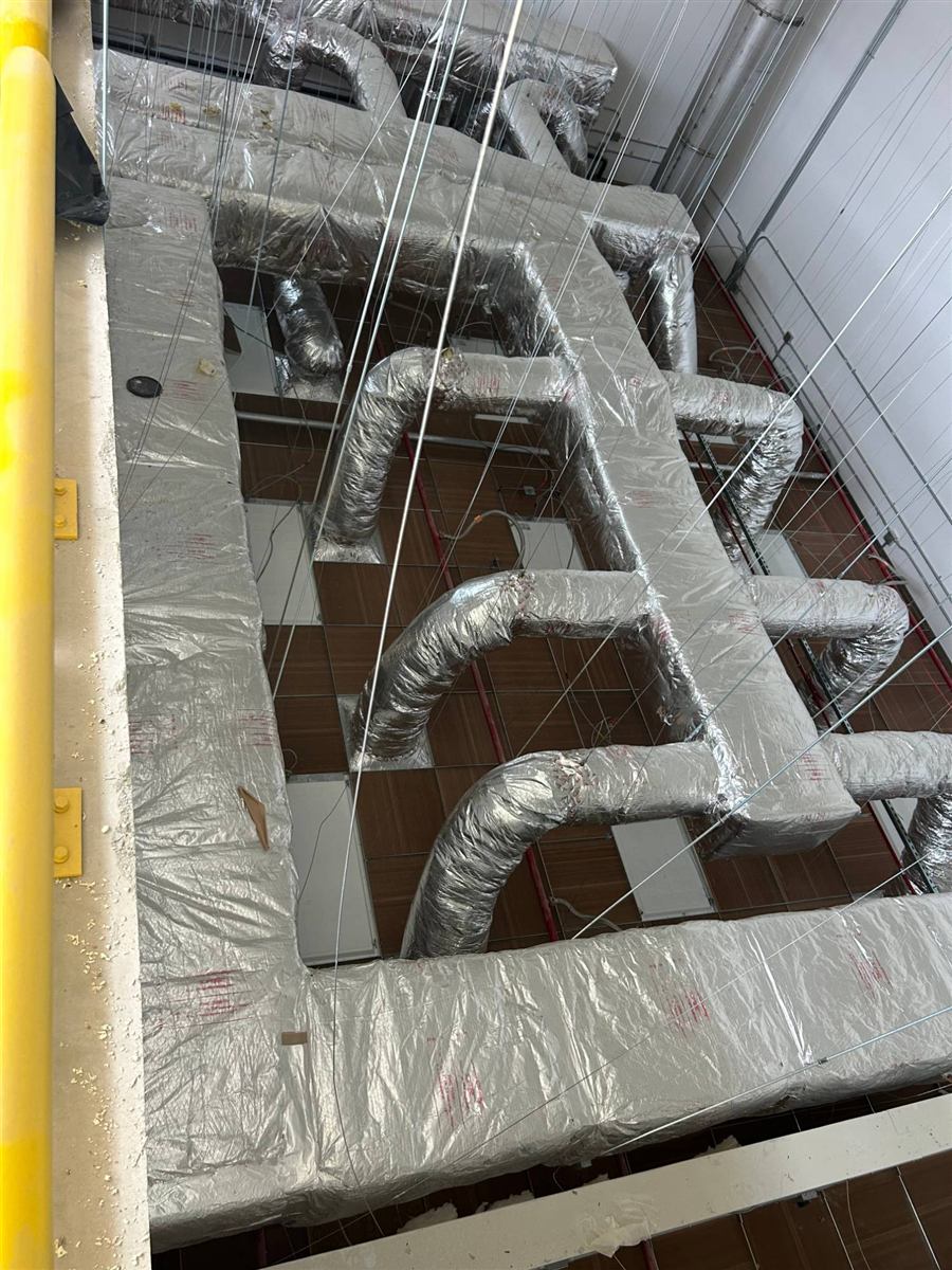 Overhead view of insulated ductwork branches above a drop ceiling